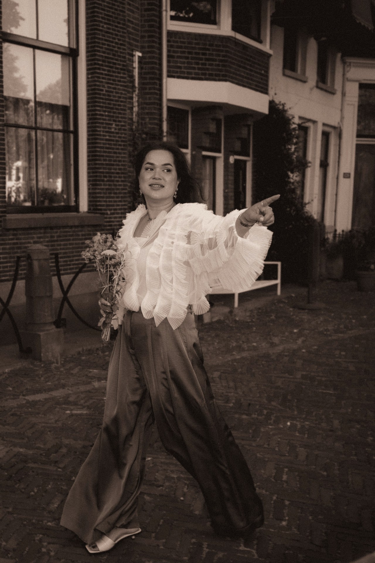 Bruid wijst lachend de weg aan in sepia getint straatbeeld