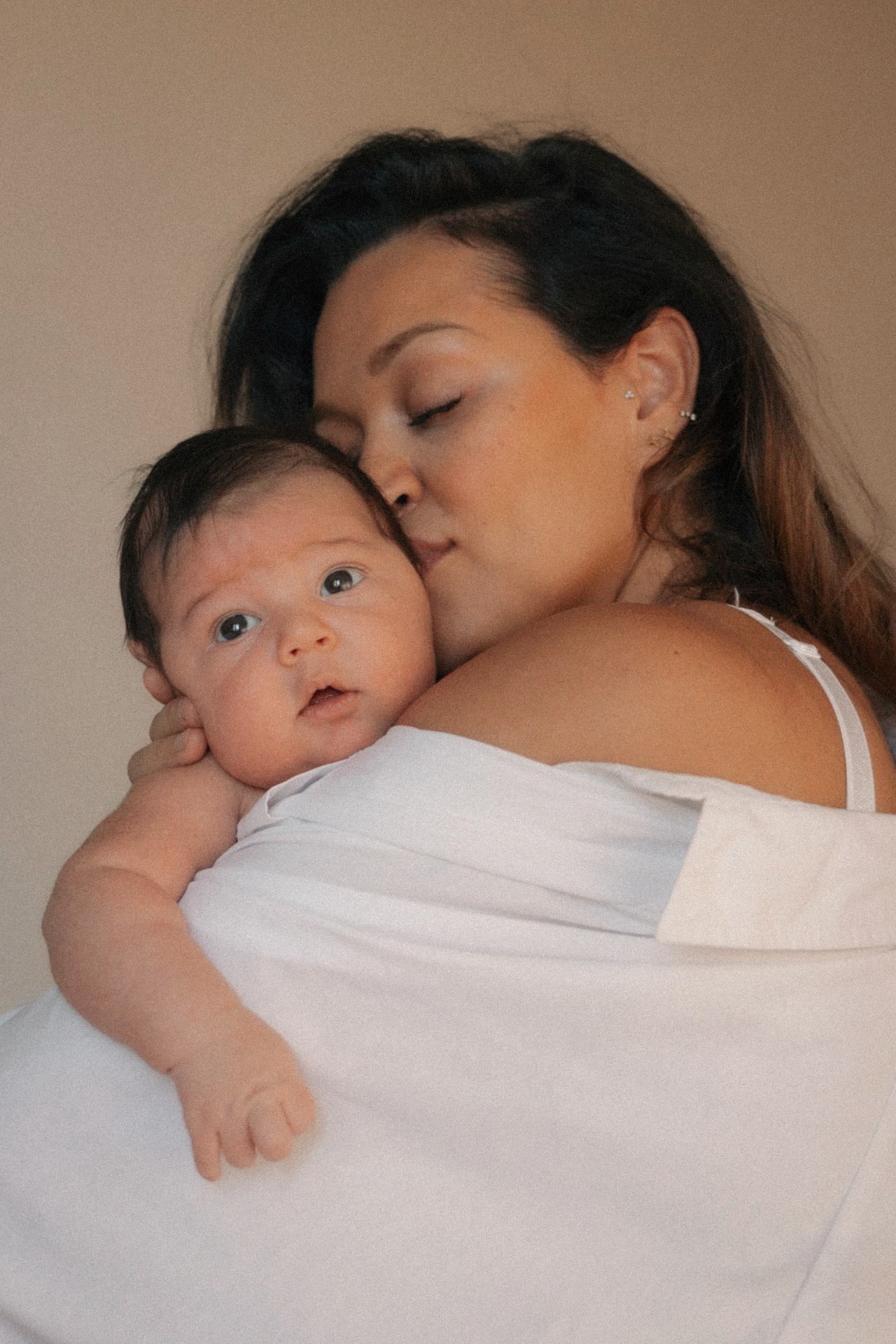 Moeder drukt een zachte kus op de wang van haar newborn