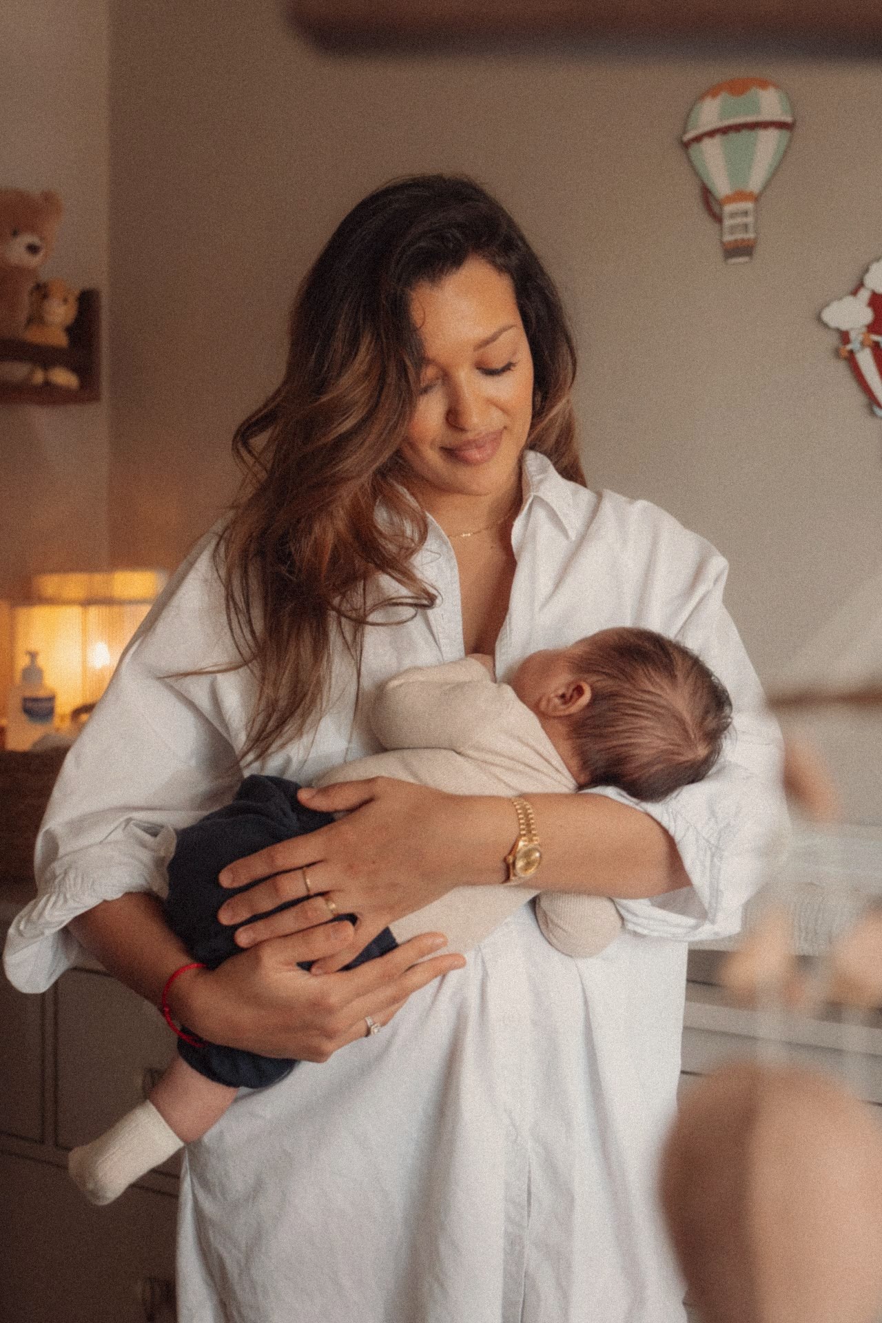 Moeder wiegt haar newborn in de babykamer met luchtballon aan de muur